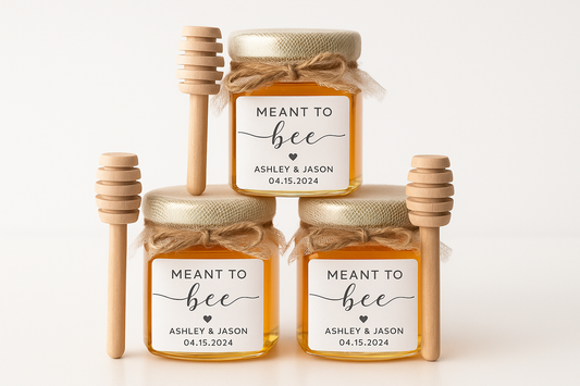 Hexagonal honey jars with "MEANT TO BEE" labels, mesh wrapping, and wooden honey dippers